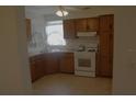 A well lit kitchen featuring wooden cabinetry, neutral countertops, tile floors and a white gas range at 1146 Alma St, Clearwater, FL 33756