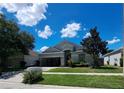 Charming single-story home with well-manicured lawn and mature landscaping under a bright blue sky at 13231 Cherry Bark Cir, Riverview, FL 33579