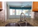 Kitchen featuring granite countertops, stainless steel sink, and a view to the outdoor swimming pool area at 1525 Albemarle Ct, Dunedin, FL 34698