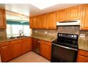 Well-lit kitchen featuring wooden cabinetry, granite countertops, stainless steel appliances, and decorative tiled backsplash at 1525 Albemarle Ct, Dunedin, FL 34698