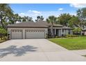 Beautiful home featuring a long driveway, three-car garage, and well-maintained lawn and landscaping at 15615 Serengeti Blvd, Spring Hill, FL 34610