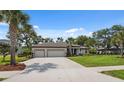 A beautiful home featuring a long driveway, three-car garage, and well-maintained lawn and landscaping at 15615 Serengeti Blvd, Spring Hill, FL 34610
