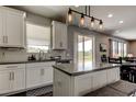 Bright kitchen featuring white cabinets, an island, and modern pendant lighting at 33176 Whisper Pointe Dr, Wesley Chapel, FL 33545