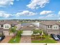 Stunning front exterior of home featuring a lake view, manicured lawn, and paver driveway at 5059 Bromeliad Ave, Wimauma, FL 33598