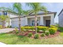 Attractive home featuring a two-car garage, stone accents, colorful bushes, and well-kept landscaping at 5059 Bromeliad Ave, Wimauma, FL 33598