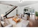 Open-concept living room with wood floors, a staircase, and a view into the modern kitchen at 8114 Pond Shadow Ln, Tampa, FL 33635