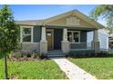 Charming home featuring a covered porch, stone accents, fresh landscaping, and a welcoming yellow front door at 936 57Th N Ave, St Petersburg, FL 33703