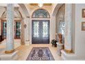Grand foyer featuring decorative columns, tile flooring, and ornate double doors with transom window at 9630 Tree Tops Lake Rd, Tampa, FL 33626