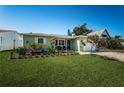 Inviting single-story home boasts a beautiful lawn, colorful landscaping, and a cozy front porch area at 12901 129Th Ave, Largo, FL 33774