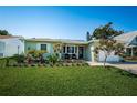 Attractive single-story home with a well-kept lawn, vibrant flowerbeds, and a quaint seating area by the entrance at 12901 129Th Ave, Largo, FL 33774