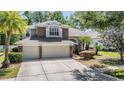 Beautiful two-story home with stone accents, a large driveway, and mature trees providing shade and curb appeal at 12712 Stanwyck Cir, Tampa, FL 33626