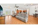 Open-concept living room features wood floors, a comfortable sofa, and leads to the modern kitchen at 21019 Lonesome Acre Rd, Wimauma, FL 33598