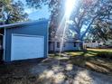 View of the one-story home with an attached garage and a driveway, surrounded by mature trees at 37654 Eiland Blvd, Zephyrhills, FL 33542