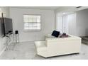 Living room featuring tile floors, a white sectional, and a large window at 5118 Tennis Court Circle, Tampa, FL 33617