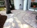 Inviting front entrance with a beautiful curved walkway, landscaped with brick pavers, and a decorative birdhouse hanging from a tree at 6410 Beaver Way, Tampa, FL 33625