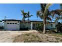 Charming single-story home featuring a white garage door, tropical landscaping, and a well-maintained lawn at 7952 1St S Ave, St Petersburg, FL 33707