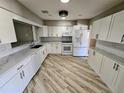 Bright kitchen features white cabinets, quartz countertops, stainless steel appliances and wood flooring at 1417 W Curlew Pl, Tarpon Springs, FL 34689