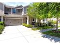 Two-story home featuring a well-manicured lawn, mature tree and an attached two-car garage at 14616 Rocky Brook Dr, Tampa, FL 33625
