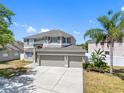 Beautiful two-story home with a three-car garage, well-manicured lawn, and mature palm trees at 19112 Cypress Green Dr, Lutz, FL 33558