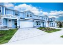Beautiful blue townhouses each include an attached garage, stone details, and verdant green lawns at 2529 Mario Way, Clearwater, FL 33761