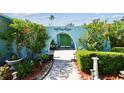 View of the entrance with a decorative archway, beautiful landscaping, and custom double front doors at 3351 San Jose St, Clearwater, FL 33759