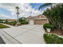 Spacious driveway leading to an attached two-car garage, bordered by mature landscaping at 617 Glastonbury Ct, Spring Hill, FL 34609