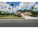Charming home featuring a manicured lawn, mature palm trees, and an attached two-car garage at 617 Glastonbury Ct, Spring Hill, FL 34609