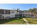 Exterior of the condo building featuring a well-maintained lawn, patio, and tropical landscaping at 7050 Sunset Way # 22, St Pete Beach, FL 33706
