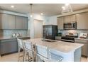 Well lit kitchen with a large center island, counter seating, stainless steel appliances, and gray cabinetry at 9943 Trellis Vine Way, Parrish, FL 34219