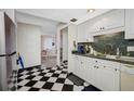 Retro kitchen design featuring black and white checkerboard floor, stainless appliances, and light wood cabinets at 1 Key Capri # 608E, Treasure Island, FL 33706