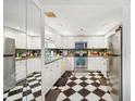Retro kitchen design featuring black and white checkerboard floor, stainless appliances, and light wood cabinets at 1 Key Capri # 608E, Treasure Island, FL 33706