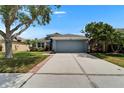 Well-maintained single-story home with a lush lawn, mature trees, and a two-car garage under a clear blue sky at 1040 Summer Breeze Dr, Brandon, FL 33511