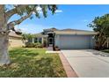 Charming single-story home with a well-maintained lawn, mature trees, and a two-car garage on a sunny day at 1040 Summer Breeze Dr, Brandon, FL 33511