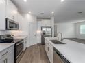 Bright kitchen with stainless steel appliances, white cabinets, quartz countertops, and wood-look tile flooring at 10446 Tupper Cay Dr, San Antonio, FL 33576