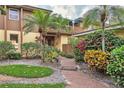 Charming home entrance with a red brick walkway, lush landscaping, and vibrant floral accents at 1058 Eldorado Ave, Clearwater Beach, FL 33767