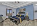 Comfortable main bedroom featuring stylish decor, wood-look floors, and a tray ceiling at 107 Sunset Dr, Nokomis, FL 34275