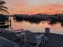 Picturesque waterfront view with a dock, boats, lounge seating, and tranquil sunset ambiance at 1311 Sea Gull S Dr, St Petersburg, FL 33707