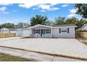 Charming single-story home featuring a minimalist landscape, garage, and blue accent door at 1427 Gerard Ln, Holiday, FL 34690
