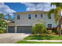 Inviting home featuring a three-car garage and lush tropical landscaping at 2463 Carnation Ct, North Port, FL 34289
