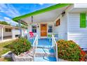 Inviting front porch with a bright orange door and colorful landscaping at 27466 Us Highway 19 N # 56, Clearwater, FL 33761