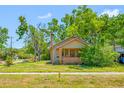 Charming bungalow featuring a brick front porch, tan siding, and a brick chimney surrounded by mature landscaping at 3100 11Th N Ave, St Petersburg, FL 33713