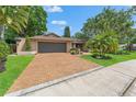 Charming single-story home with mature landscaping, brick driveway, and inviting curb appeal on a sunny day at 3320 Pattie Pl, Palm Harbor, FL 34685