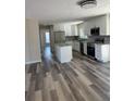 Open-concept kitchen with stainless steel appliances, white cabinets, and luxury vinyl plank flooring at 4212 Pasadena Cir, Sarasota, FL 34233