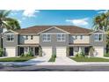 New construction townhome with tan stucco exterior, attached garages, and tropical landscaping under a bright blue sky at 429 Warm Heron Pl, Ruskin, FL 33570