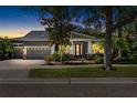 Twilight view of a modern home showcasing a three-car garage, manicured lawn, and inviting front porch at 5313 Sanderling Ridge Dr, Lithia, FL 33547