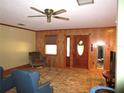 Inviting living room with paneled walls, neutral paint, a ceiling fan and a front entrance at 5602 N Dormany Rd, Plant City, FL 33565