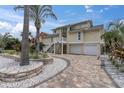 Two-story yellow home with two-car garage, landscaped yard and white staircase at 633 Soundview Dr, Palm Harbor, FL 34683