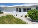 Front yard featuring a pristine white exterior, a well manicured lawn, and blue shutters at 9035 37Th N St, Pinellas Park, FL 33782