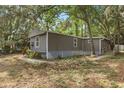 Quaint gray home with verdant foliage, set back from the road, offers a peaceful setting at 9132 Mango St, New Port Richey, FL 34654