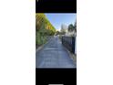 Long black asphalt driveway gated with metal and greenery surrounding the sides at 9900 Ideal Ln, Hudson, FL 34667